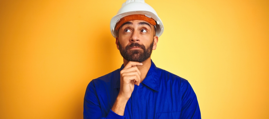 a contractor in a hard hat holding his chin, pondering