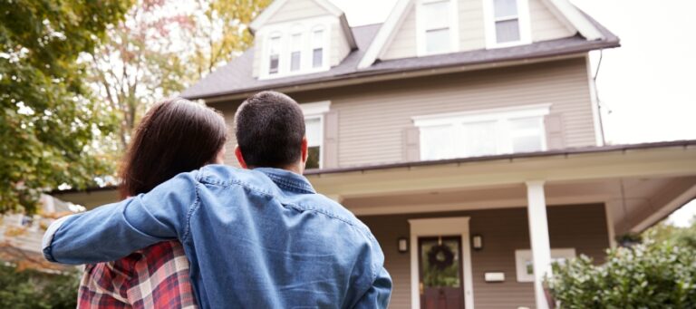 a man and a woman hold each other as they look at a house