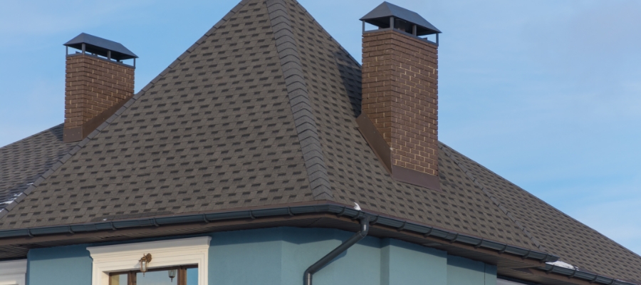 an angular roof with 2 chimneys surrounded by flashing