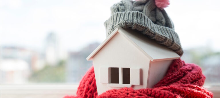 Wooden home wrapped in winter scarf and hat