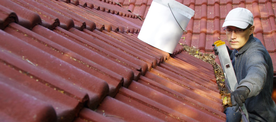 The man cleans the gutters on the roof